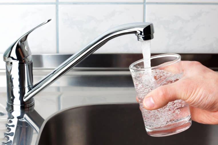 pouring tap water from faucet into glass